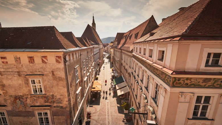 View of a historic street in the old town of Krems with old buildings and people taking a walk.