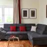 Modern living room with gray sofa, red cushions, glass table and artwork on the wall.