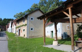 Historic buildings in Althöflein with an old timber press shelter in the foreground.