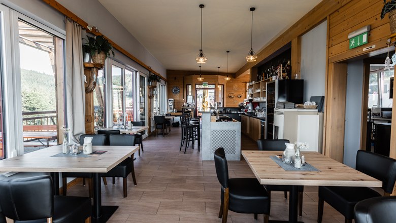Interior view of a modern café with wooden furniture and large windows.