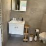 Modern bathroom with washbasin, mirror, toilet and shelves.