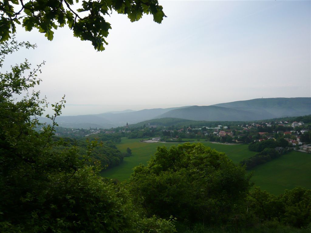 View of Gießhübl with green hills and trees in the foreground.