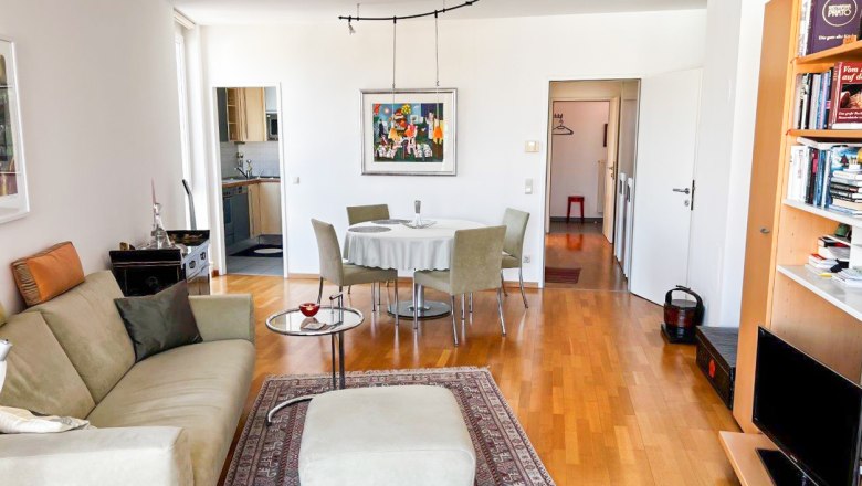 Living room with sofa, carpet, dining table and bookshelf.