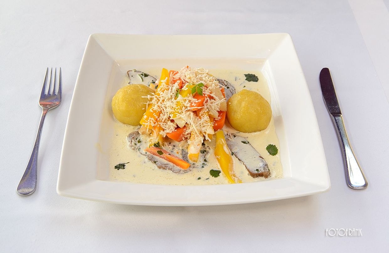A plate of horseradish meat, potatoes and vegetables in a cream sauce.