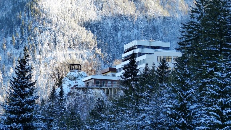 Winter view of the Sporthotel Semmering surrounded by snow-covered trees and mountains.