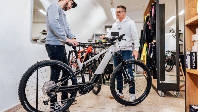 Two men look at a bicycle in a bicycle store.