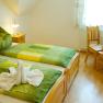 Cozy guest room with double bed, green bed linen and wooden furniture.