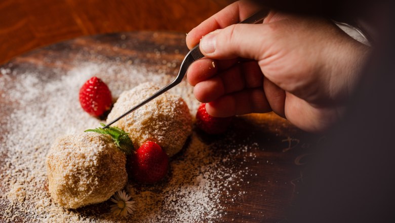 Hand-decorated dessert with strawberries and mint on a wooden platter.