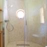 Modern shower with round glass wall and small porthole.
