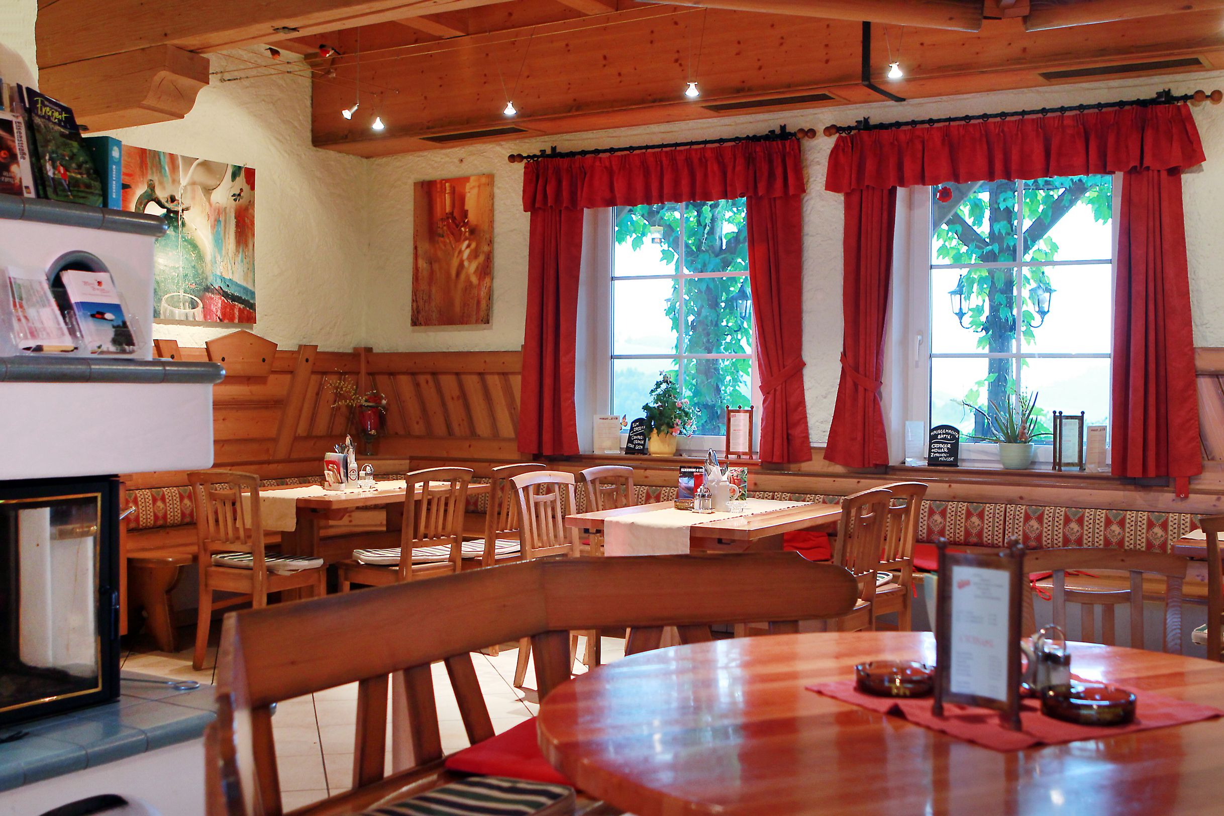 Cozy interior of a traditional Austrian wine tavern with wooden furniture and red curtains.