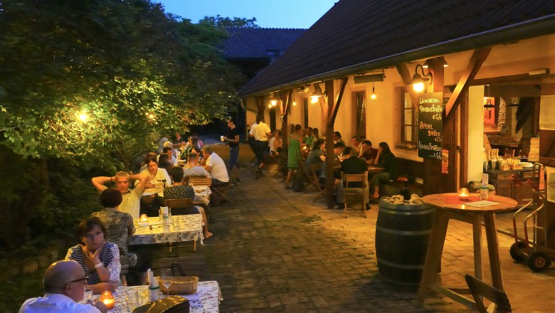 People sitting in a cozy outdoor area of a Buschenschank (typical tavern) in the evening.