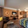 Modern hotel room with wood paneling, sofa, bed and flat-screen TV.