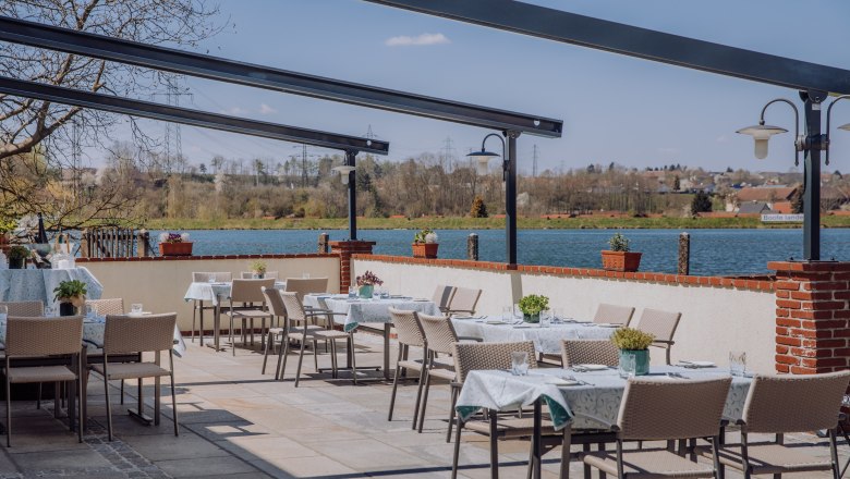 Terrace with tables and chairs, view of a reservoir and the surrounding countryside.
