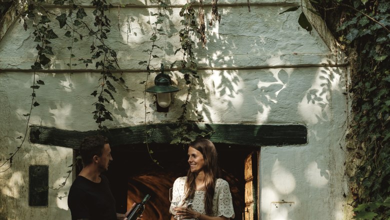 A man and a woman are standing in front of a wine cellar labeled 'SB Keller'.