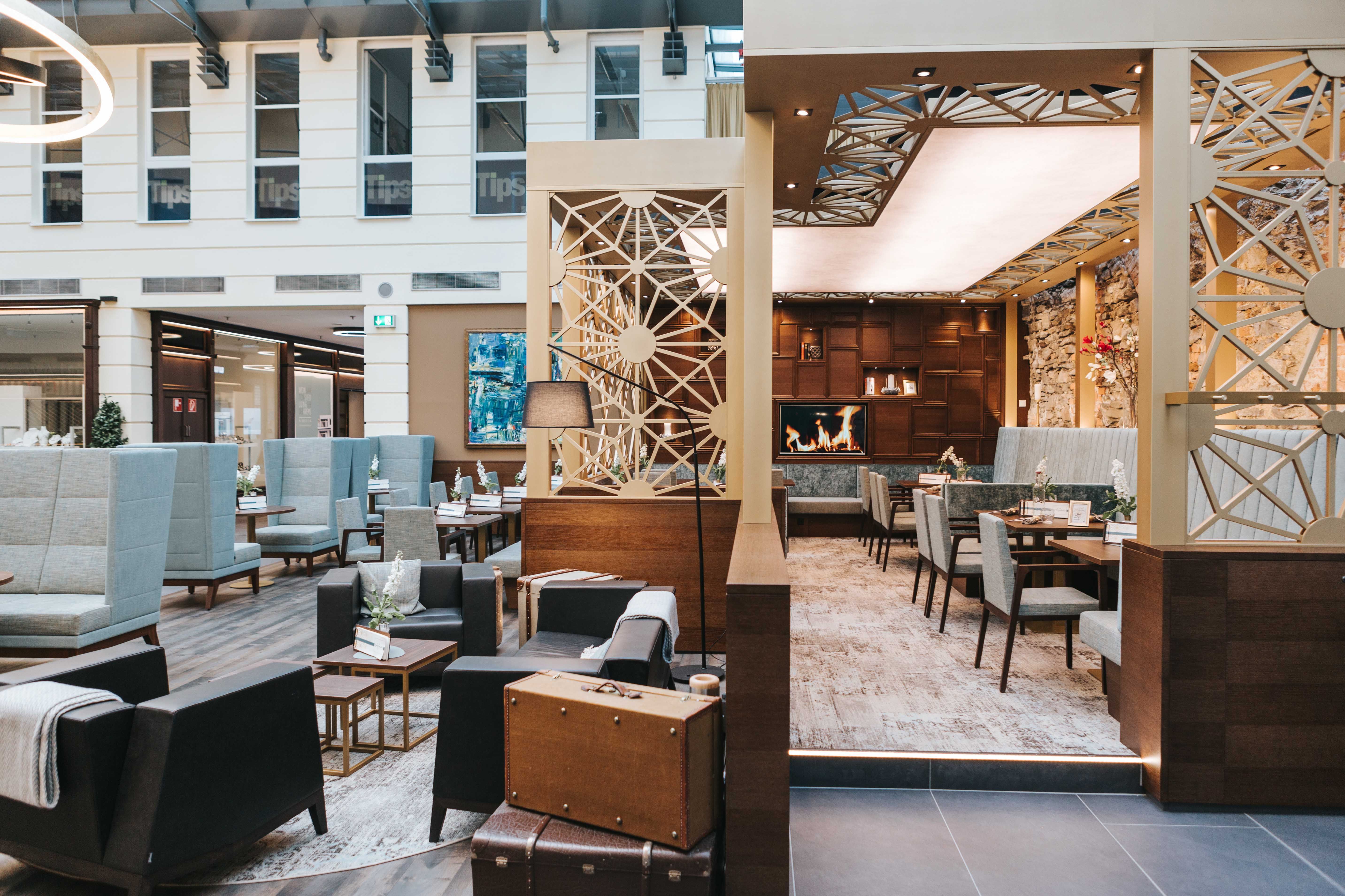 Interior view of a modern café with cozy seating areas, fireplace and stylish decoration.