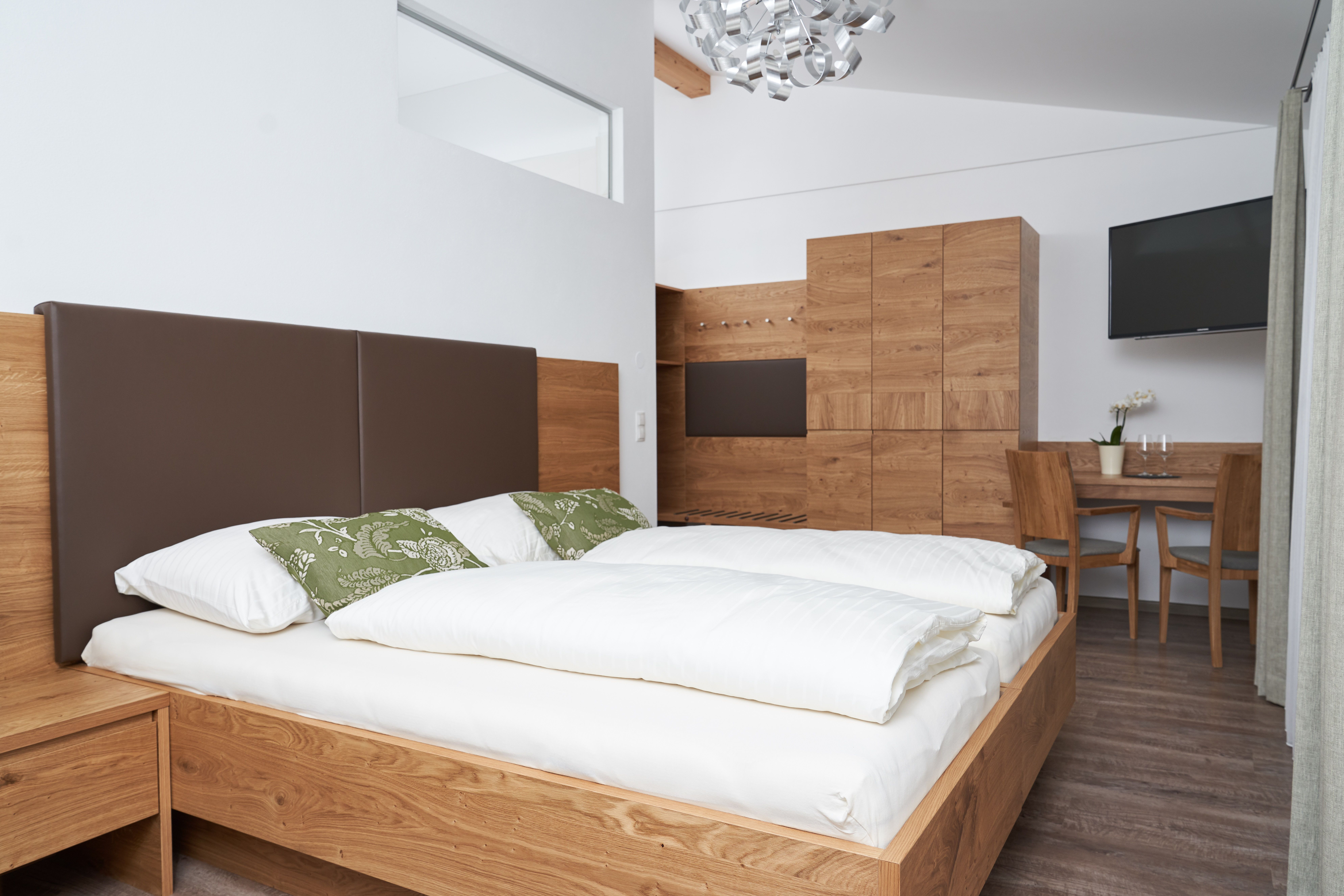Modern bedroom with wooden furniture, double bed, table and chairs.
