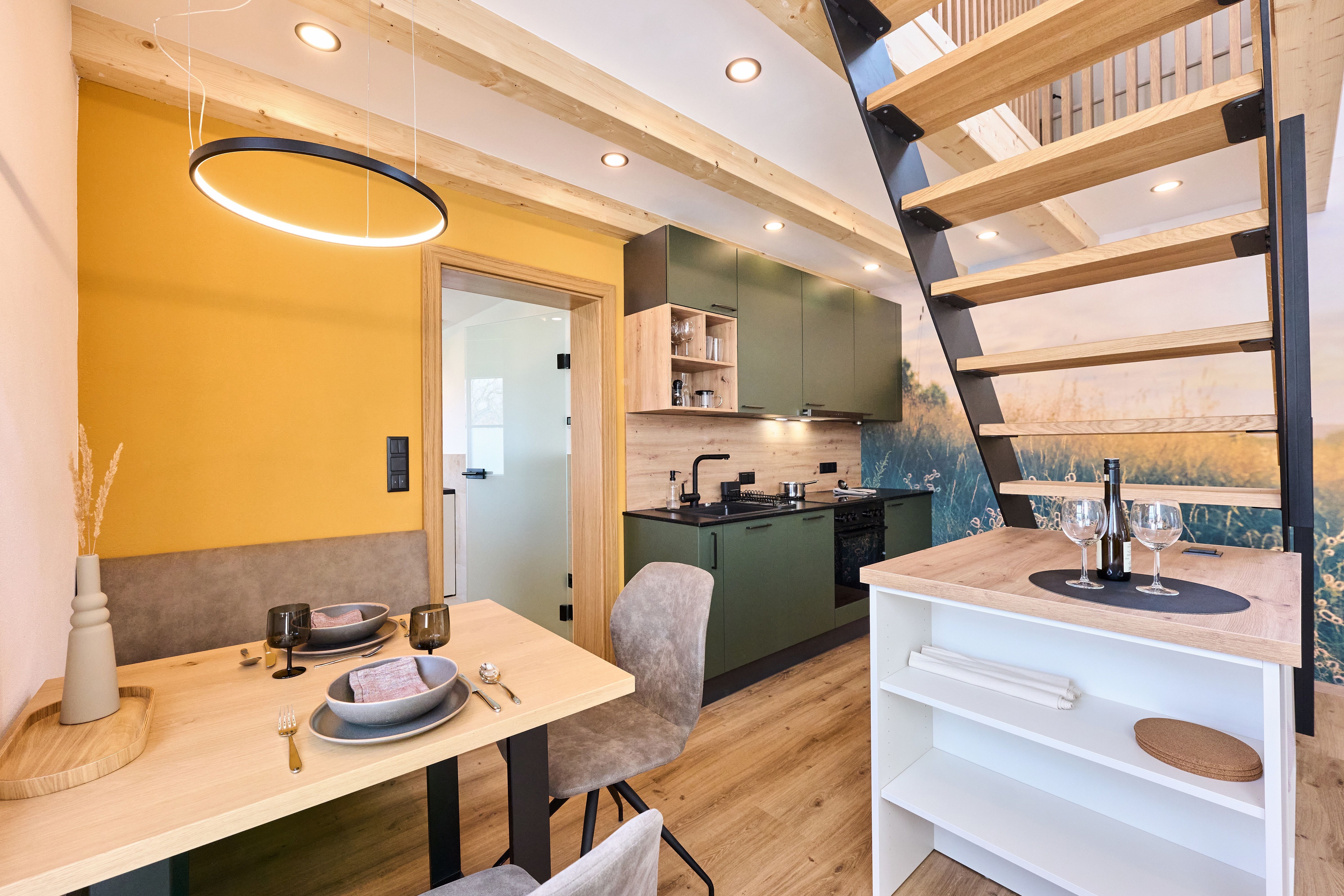 Modern interior of a small house with kitchen, dining table and staircase.