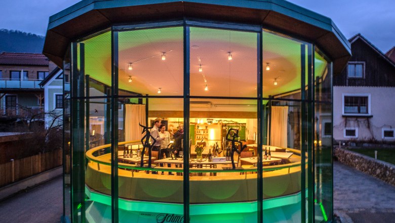 Exterior view of a modern, glazed building at dusk with illuminated interior.