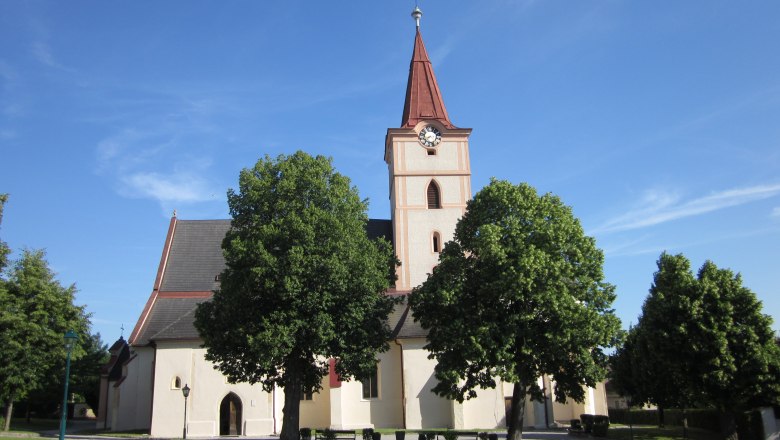 Pyhra parish church with tower and trees in the foreground.
