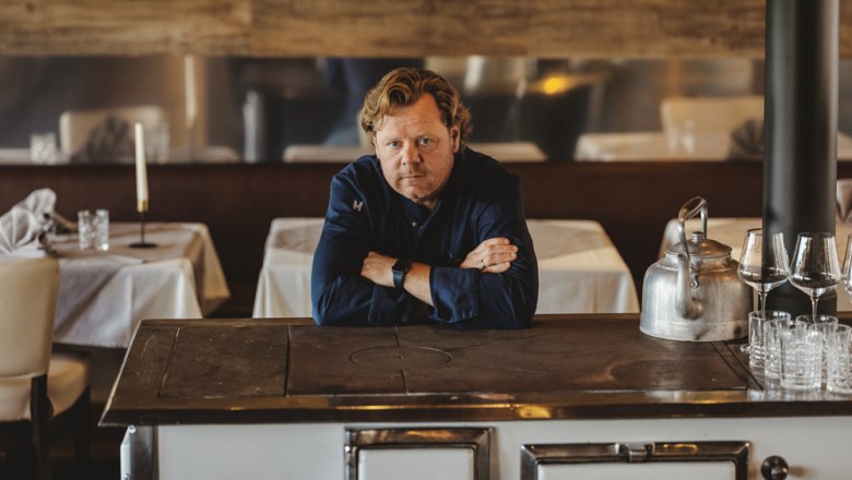 Man leaning on an antique stove in an elegant restaurant.