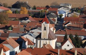 Aerial view of the Getzersdorf parish church with surrounding houses and fields in the fall.