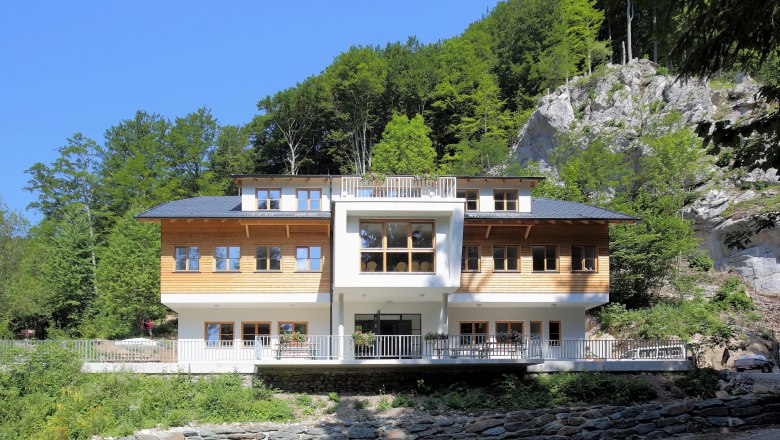 Weichtalhaus, © BwagCommons A modern building with a wooden façade in front of a wooded slope.