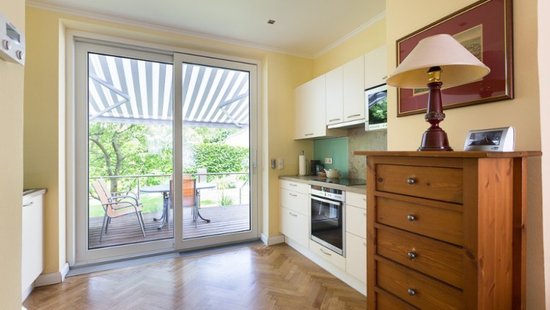 Kitchen, © Creative Design Bright kitchen with parquet floor, cupboard, stove and large glass door to the terrace with awning.