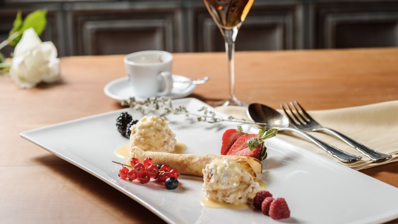 Elegant dessert with fruit and ice cream on a white plate, accompanied by a glass of wine and a cup of coffee.
