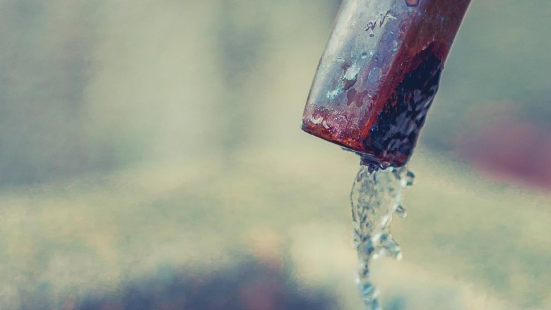 Close-up of a jet of water flowing out of a metal pipe.