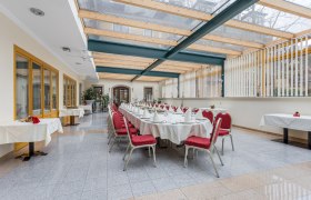 Elegant conservatory with table setting and red chairs.