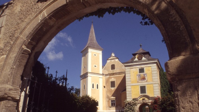 Historic building with tower seen through a stone archway.