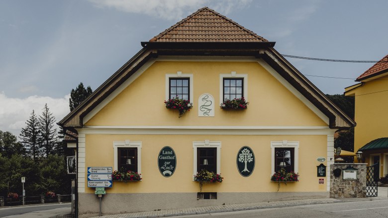 Yellow inn with flower boxes and signs on the façade.