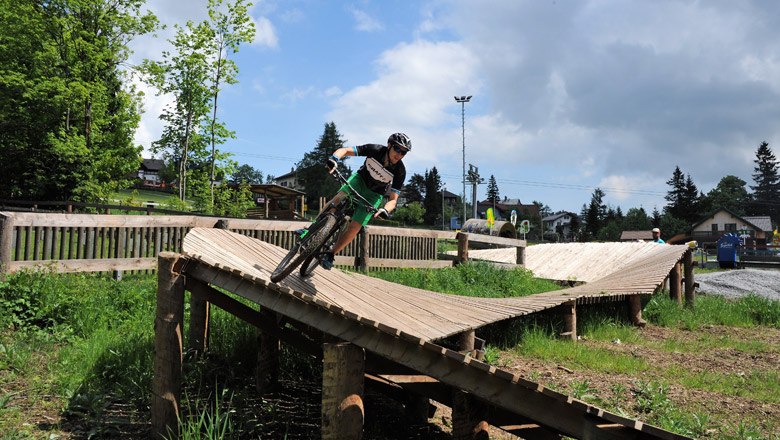 Child riding on a wooden ramp in Bikepark Semmering.