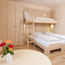 A cozy guest room with bunk beds, wooden furniture and a table with flowers.