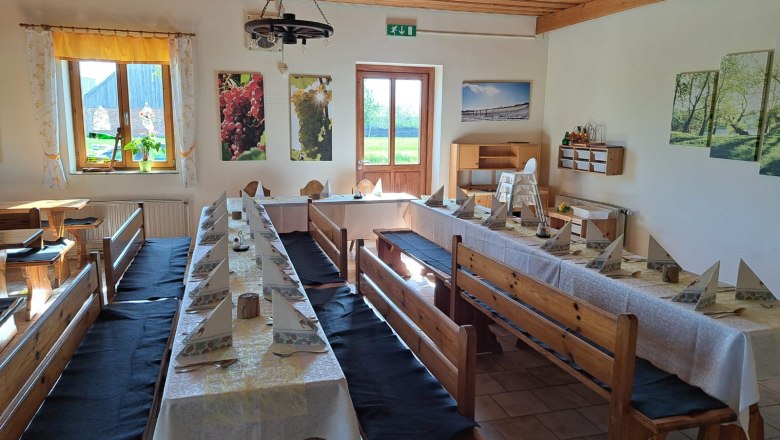 Interior view of a rustic dining room with wooden benches and laid tables.