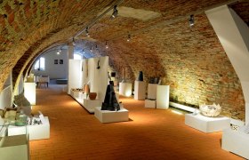 Exhibition space with brick walls and works of art on pedestals.