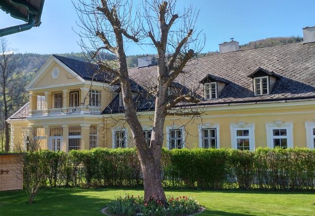 Yellow building with balcony and garden in the foreground.
