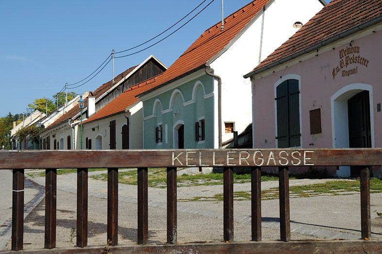 Historic wine cellar lane in Grafenwörth with colorful buildings and a wooden fence in the foreground.