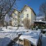 Snow-covered garden with table and chairs in front of a yellow house.