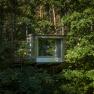 A modern tree house in the middle of a dense forest.