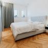 Modern bedroom with double bed, parquet floor and gray curtains.