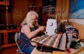 A woman sews on a sewing machine in a craft studio.