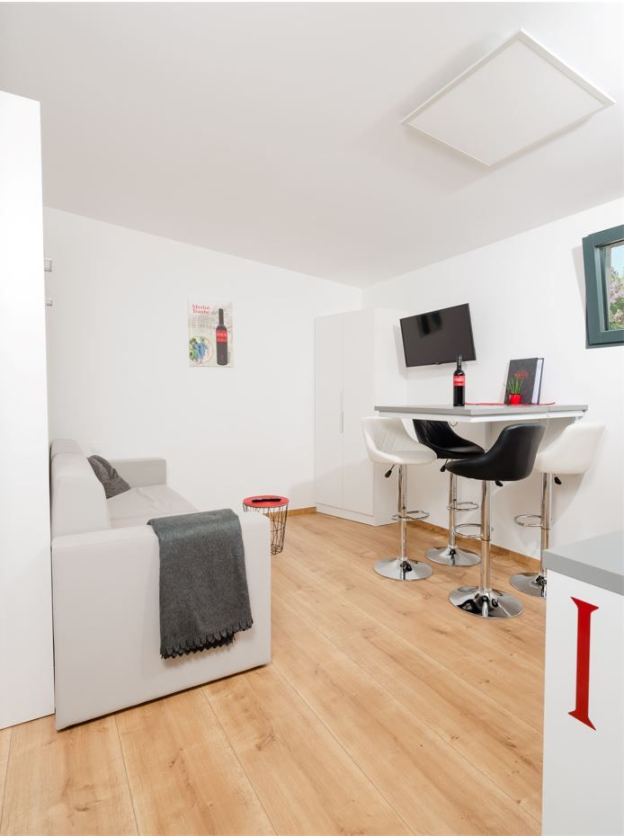 Modern living room with sofa, dining table and bar stools.