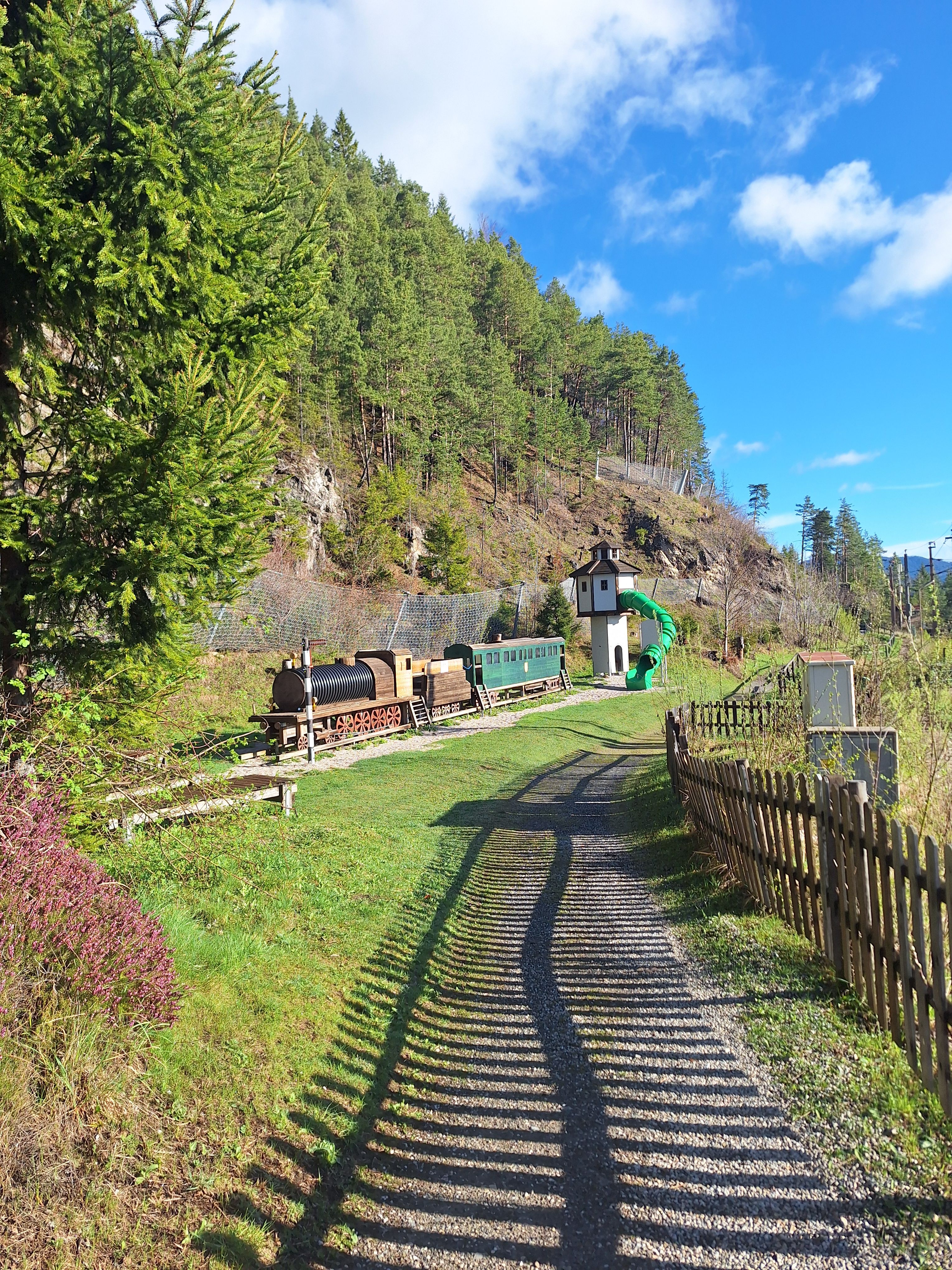Children's playground with a wooden locomotive and a slide tower. 