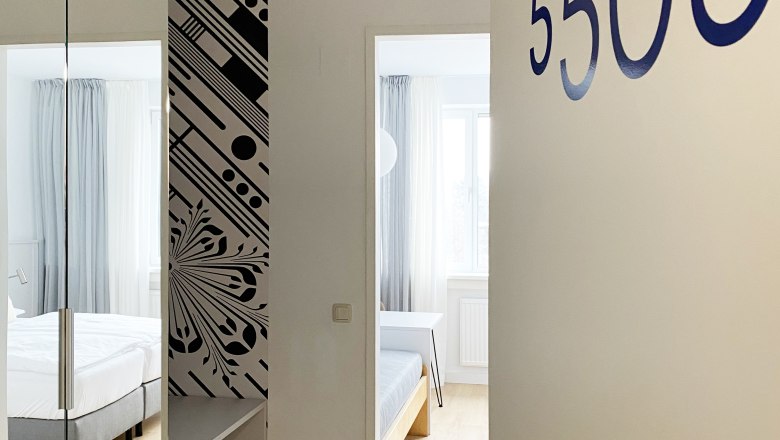 View of a guest room with the number 5505, modern furnishings with bed and mirror.