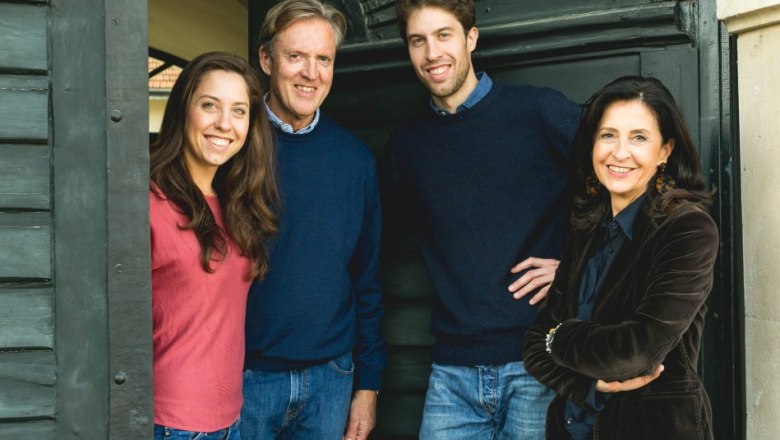 Four people stand smiling in a doorway, two men and two women, all in casual clothes.