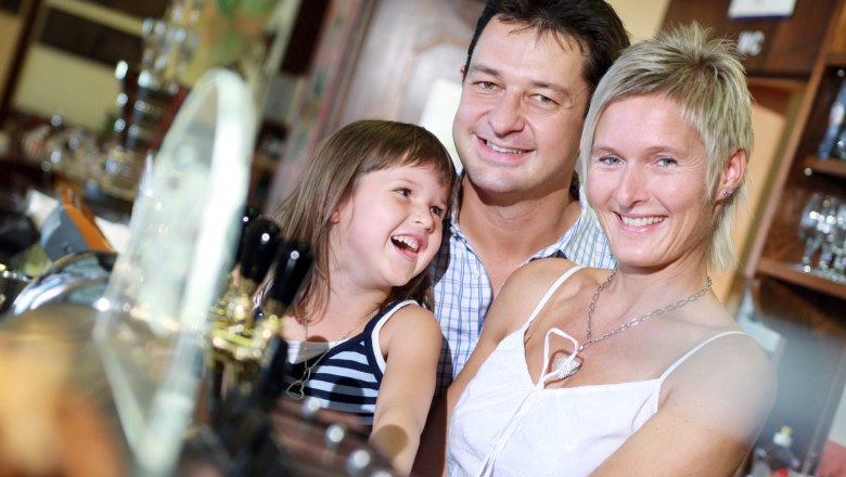 A smiling family stands at the bar in a restaurant or hotel.