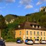 A yellow building against a mountain backdrop with parked cars in front of it.