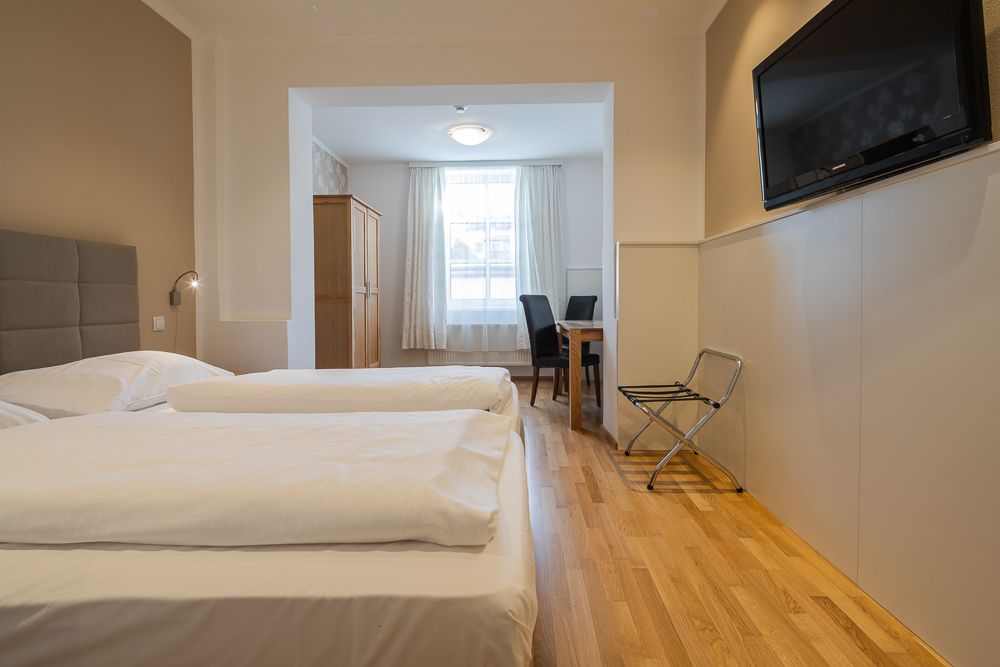Hotel room with two beds, TV, table and chairs.