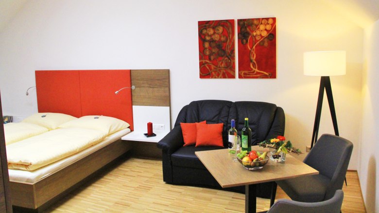 Cozy room with double bed, sofa, table and floor lamp.